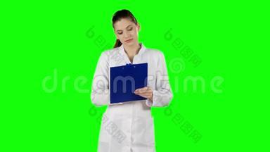 护士或年轻医生写在医疗文件夹板上。 绿色屏幕