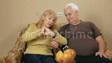 年长夫妇在家里的沙发上看智能手表上的信息。 他们仔细<strong>阅读</strong>并<strong>阅读</strong>重要的文章