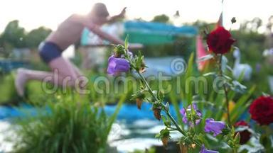 在<strong>炎热</strong>的<strong>夏天</strong>，孩子们在一个小湖里游泳。 男孩跳进水里，造成水溅。 花园