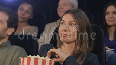 在电影院，女人把爆米花放进嘴里