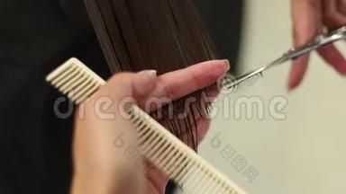 理发师给女人做发型。 剪发特写.. 剪刀和梳子在发型师。 一头漂亮的头发