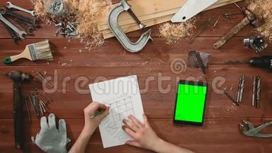 顶层工匠手画橱柜草图，数码平板绿屏躺在书桌上