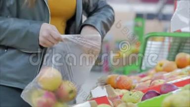 漂亮的年轻漂亮的红发女人在市场上，在超市里买食物、水果、苹果。 女孩选择