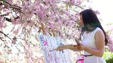 一位美丽的女画家，穿着白色的衣服，画家在盛开的春天苹果园里画了一幅花，她