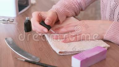 女人在指甲上涂上一层紫胶。 特写双手。