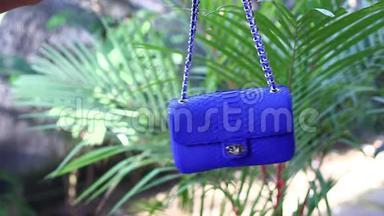 时尚豪华蛇皮蟒手袋在热带花园背景下运动。 巴厘岛。 小蓝包。