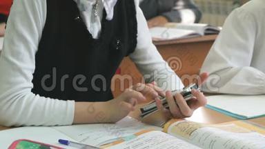 学生女孩坐在课桌旁拿着智能手机