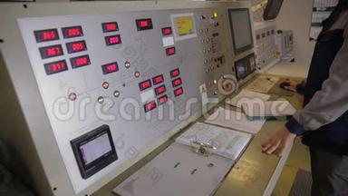 工程师在控制室和发电厂的控制面板附近工作。 测量结果的书写。