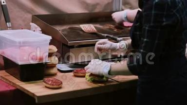 一个白手套的厨师做汉堡。 男人把汉堡和肉串放在最上面，把每个汉堡都穿在后视图上