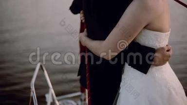 新婚夫妇在游艇的鼻部拥抱的近景。 在船上举行婚礼
