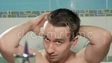 年轻有魅力的男人在酒<strong>店</strong>房间的浴室里洗过澡后，就会挺直发型。 他<strong>双</strong>手梳着头发