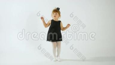 可爱的小女孩穿着黑色的裙子跳舞，玩得很开心，被隔离在白色的身上