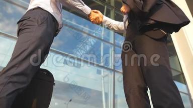 办公楼附近室外商务握手.. 两个商人在城市环境中互相问候。 晃动
