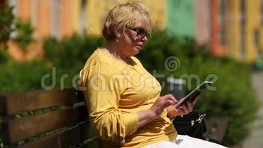 穿黄色夹克的女人用电子书。 女人拿着电子书
