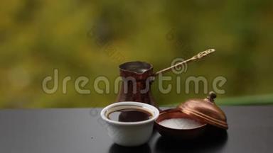 在白色咖啡杯中提供美味的热咖啡，在传统的土耳其锅中酿造糖，在室外提供咖啡桌