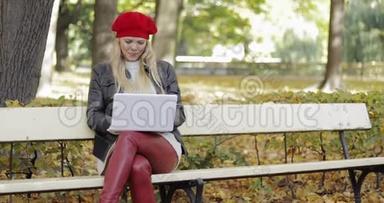 微笑的女人在公园里用笔记本电脑