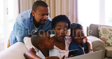 <strong>家长</strong>和孩子在沙发上使用笔记本电脑和智能手机