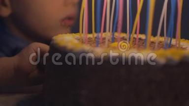 体贴的男孩试着用蛋糕和<strong>蜡烛</strong>做手指霜。 男孩在慢动作的生日蛋糕上吹<strong>蜡烛</strong>