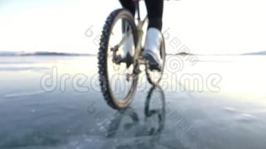 轮胎的视图。 拍摄180fps.. 女人在冰上骑自行车。 冰的贝加尔湖。 上面的轮胎