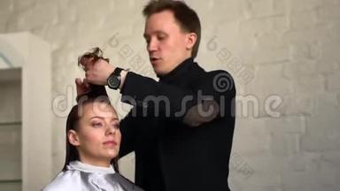 男美发师在美容院给女孩子做发型。