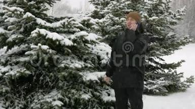 一个年轻人在冬天的森林里打电话。 大雪纷飞。 他停下来结束了谈话。 一个男人