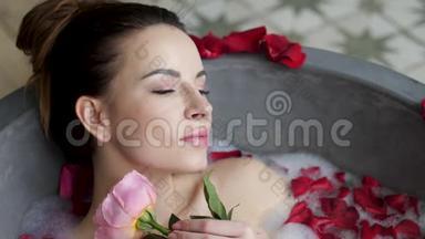 小女孩躺在一个大石头浴缸里，手里拿着一朵玫瑰花