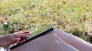 女孩用平板电脑，坐在田野的树下，特写