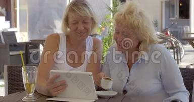 <strong>两</strong>位年长的妇女在街边咖啡馆的垫子上看照片