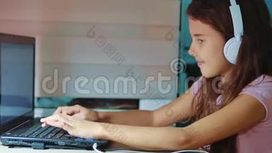 小<strong>女孩</strong>带着耳机在笔记本电脑上玩<strong>网络</strong>游戏。 电脑上的小<strong>女孩</strong>在<strong>社交</strong>中写了一条信息