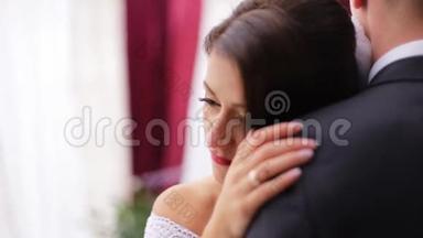 美丽的新娘感到受到保护，并真的很高兴`丈夫的手，并拥抱他在他们的婚礼当天。