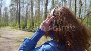 公园里的一个年轻女孩戴着耳机听音乐。 一个女人参加运动，喜欢耳机里的音乐。