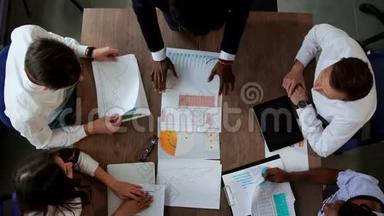 各民族创意经理办公室团队在大办公桌<strong>后面</strong>的俯视图