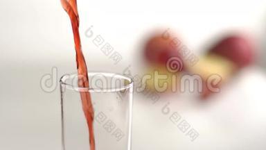在工作室里模糊的苹果背景下，高高的玻璃杯正在高速地装满红色的果汁