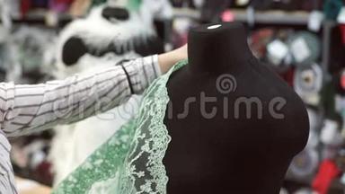 在服装店推销员试图绿色花边裁剪人体模型。