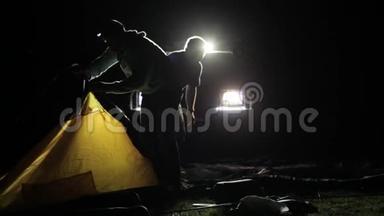 两名成年男子和儿童从越野车上搭帐篷的夜间镜头。