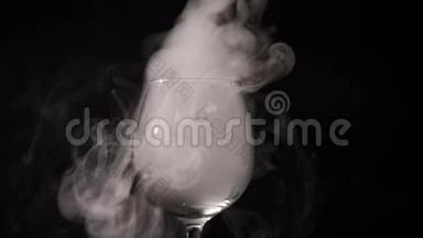 在黑暗中，白色的烟雾在一个空的透明玻璃中盘旋。