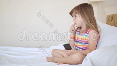 可爱的孩子穿着五颜六色的衣服在床上看电视