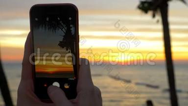 一个带着<strong>手机</strong>的女人在<strong>日</strong>落时拍了一张热带海滩的照片。