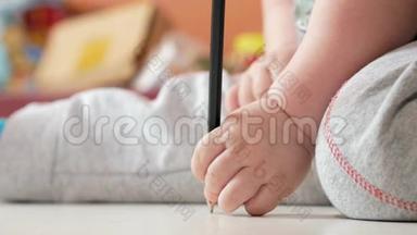 一个2岁的男孩在家里用<strong>彩色铅笔画</strong>画。 手里是黑色的。