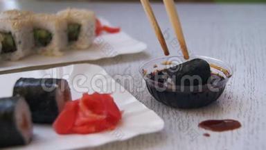 一家日本餐馆的筷子夹着<strong>酱油</strong>里的诺丽<strong>寿司</strong>卷。 慢动作