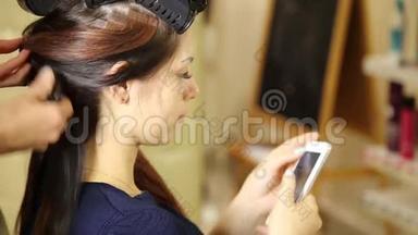 年轻女子在美容院，理发师给漂亮模特做发型。 顾客在电话里交谈