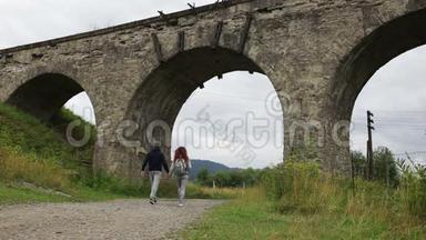 幸福的一对夫妇沿着老高架桥下的路走着