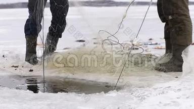 渔民把<strong>鱼</strong>从<strong>冰冻</strong>池塘的洞里拉出来。