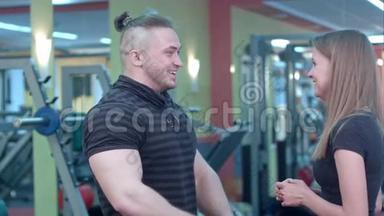 微笑的年轻女子在健身房和她的私人教练交谈