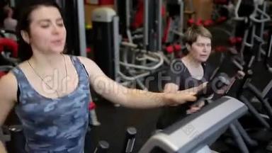 两个女人在健身房里使用运动机。 一群女人。 女孩在窗户上做运动。 体育运动。 健身房