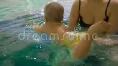 一位年轻的母亲带着一个小男孩游泳，在游<strong>泳池里</strong>玩得很开心。 快乐的小男孩和他一起在游<strong>泳池里</strong>游泳