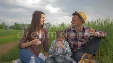 大自然的娱乐，快乐的微笑家庭与孩子在户外绿野野餐时喝牛奶
