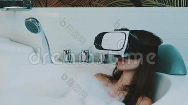 女孩在浴室里用<strong>虚拟现实</strong>眼镜洗满泡沫的澡。 <strong>微笑</strong>
