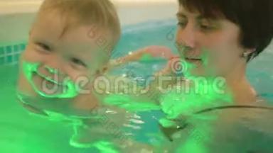 一位年轻的母亲带着一个小男孩游泳，在<strong>游泳池</strong>里玩得很开心。 快乐的小男孩和他一起在<strong>游泳池</strong>里游泳