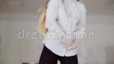 一个穿着白色上衣的女孩在工作室里排练舞蹈。